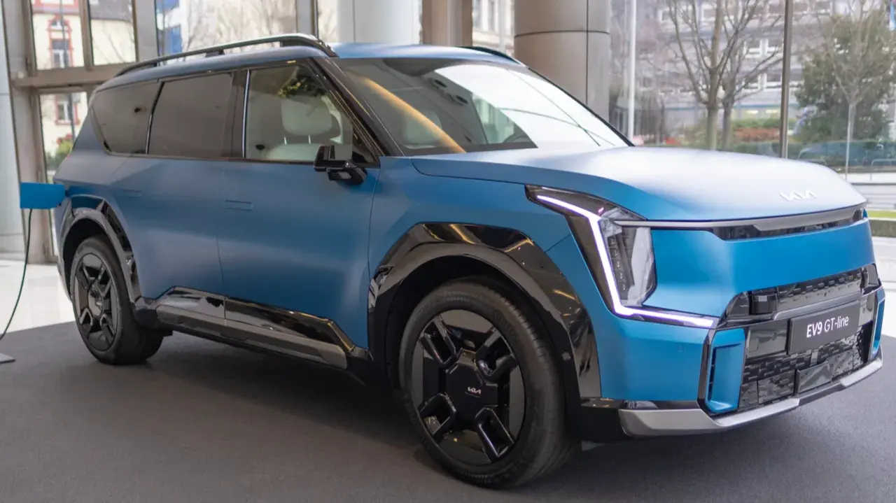 Blue electric Kia EV9 displayed in a showroom.