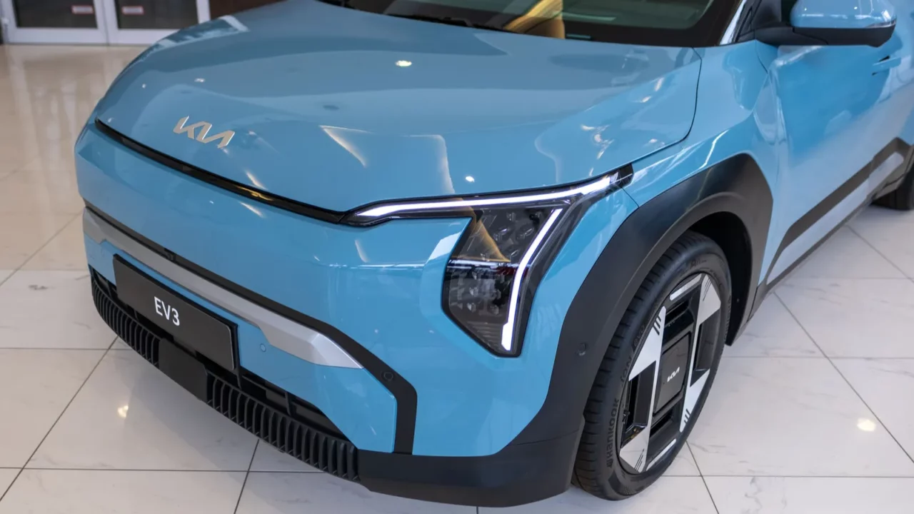 Cropped front view of blue Kia EV3 displayed at a showroom.