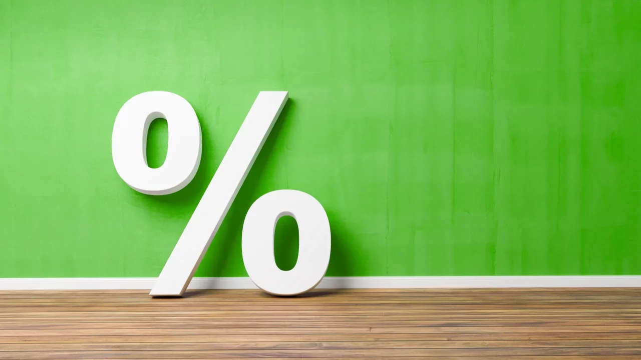 white percent sign on brown wooden floor against green wall