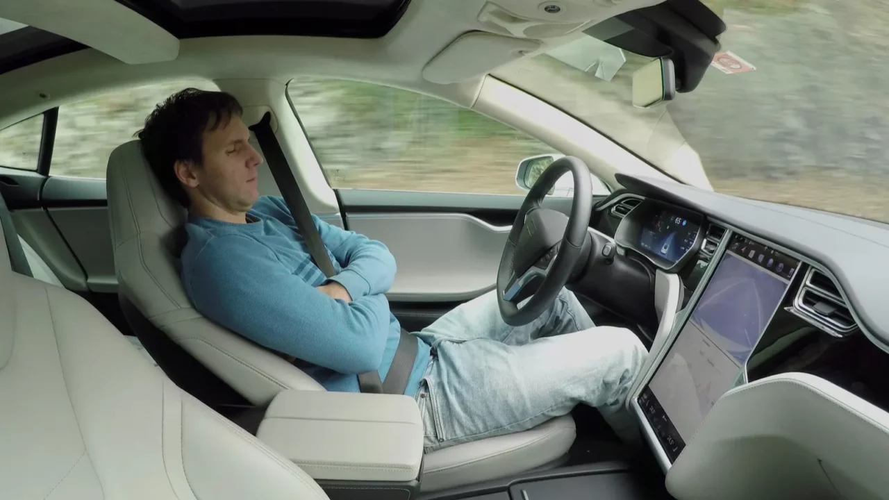 A shot of a male driver sitting back and relaxing as the car navigates in self-driving mode.